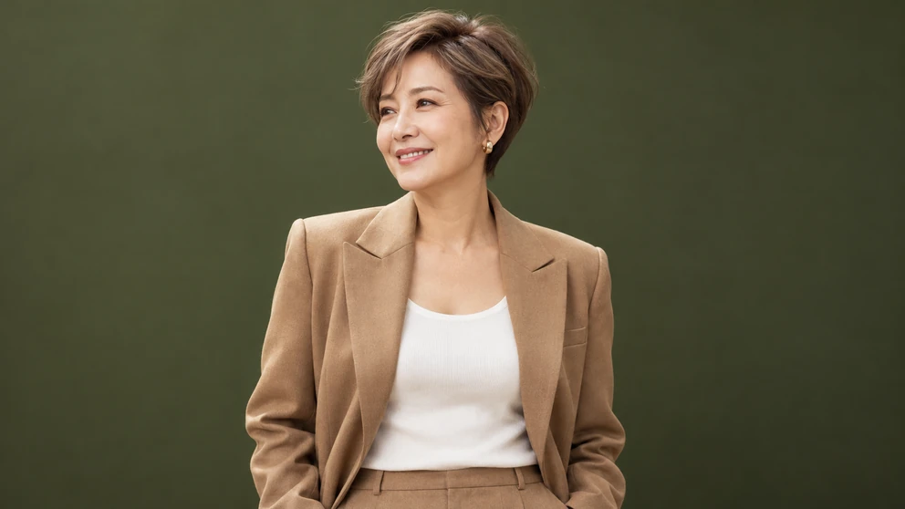 밀크티 베이지 브라운 숏컷을 한 50대 초반 여성이 카멜 재킷 차림으로 밝게 웃는 허리 위 화보 컷, 정수리 결이 자연스럽게 살아 있음